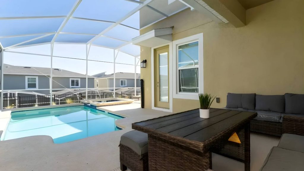 Área de terraza con mesa y sofás junto a una piscina privada.