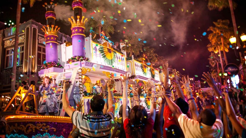 Desfile nocturno de Mardi Gras con carrozas iluminadas y confeti.