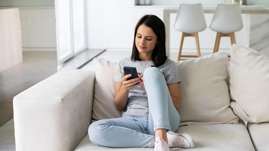 girl on sofa using her cell phone