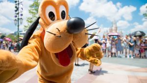 Mascota del parque saludando visitantes en Disney World Orlando con el castillo al fondo en un día soleado